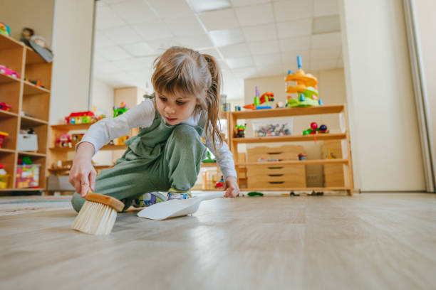 Toddler independently sweeping with a dustpan at home