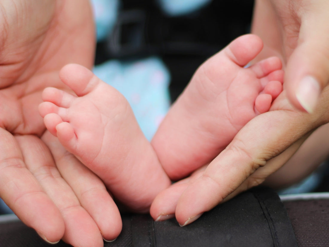 A parent holding her babies' feet in her hands.