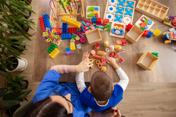 Overhead view of a child and adult playing with wooden and colorful Montessori toys on the floor