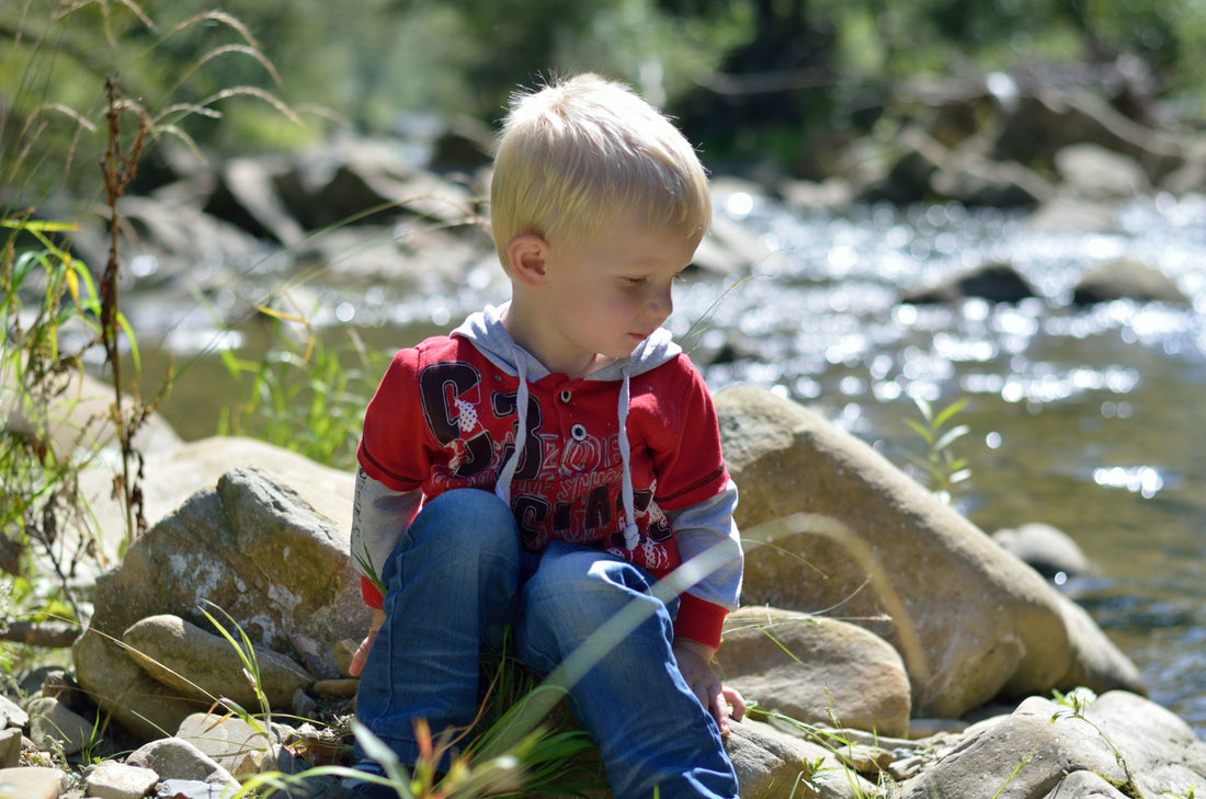 child enjoying the outdoors beside a stream
