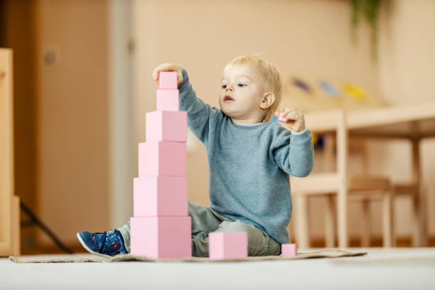 Child building a pink Montessori tower with wooden blocks