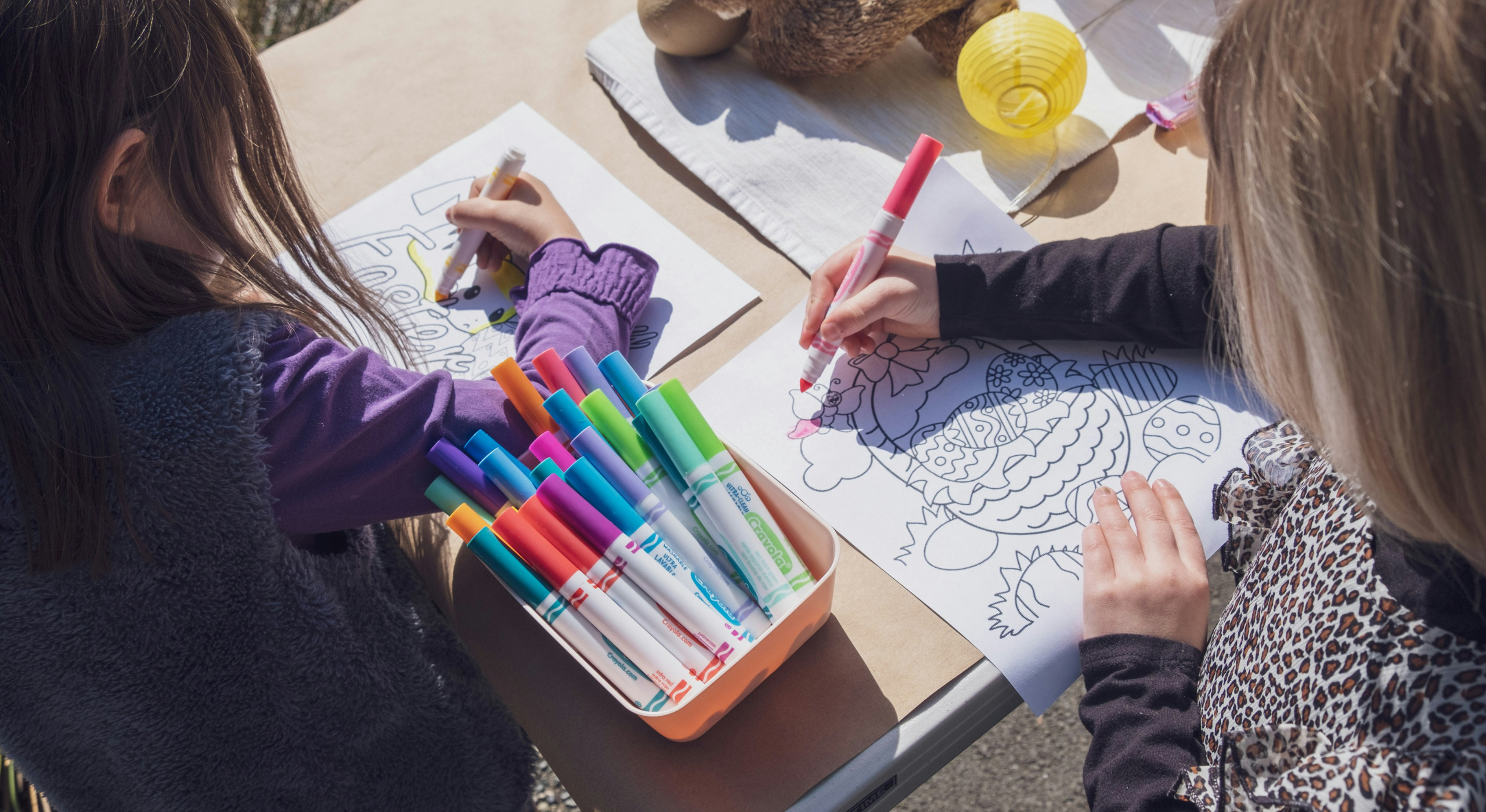 Children coloring with markers, focusing on creativity and educational play, aligns with Oliver & Company Montessori Toys' emphasis on early learning and creativity.