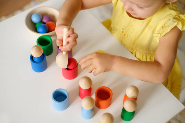 A toddler playing with eco-friendly wooden toys, including colorful balls and various shaped objects, promoting educational and independent play.