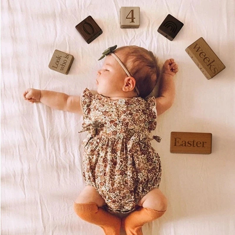 A baby lying on a bed surrounded by wooden blocks, reflecting Oliver & Company Montessori Toys' focus on educational and eco-friendly products for infants.