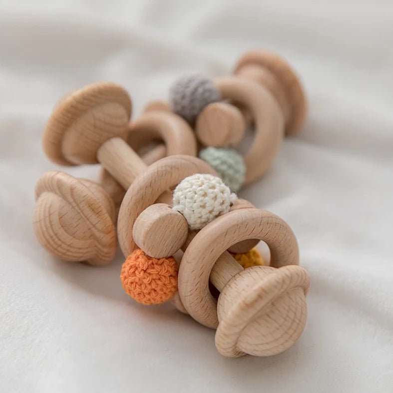 Wooden baby rattle on a white blanket, showcasing natural materials aligned with Oliver & Company Montessori Toys' eco-friendly, educational focus.