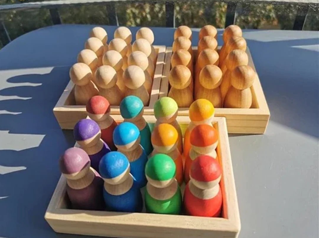 A collection of colorful wooden toy figures and balls, showcasing eco-friendly, educational toys from Oliver & Company Montessori Toys.