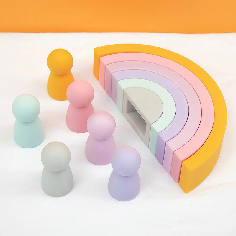 Set of pastel-colored silicone toys including rainbow-shaped blocks and small round figures on a white background.