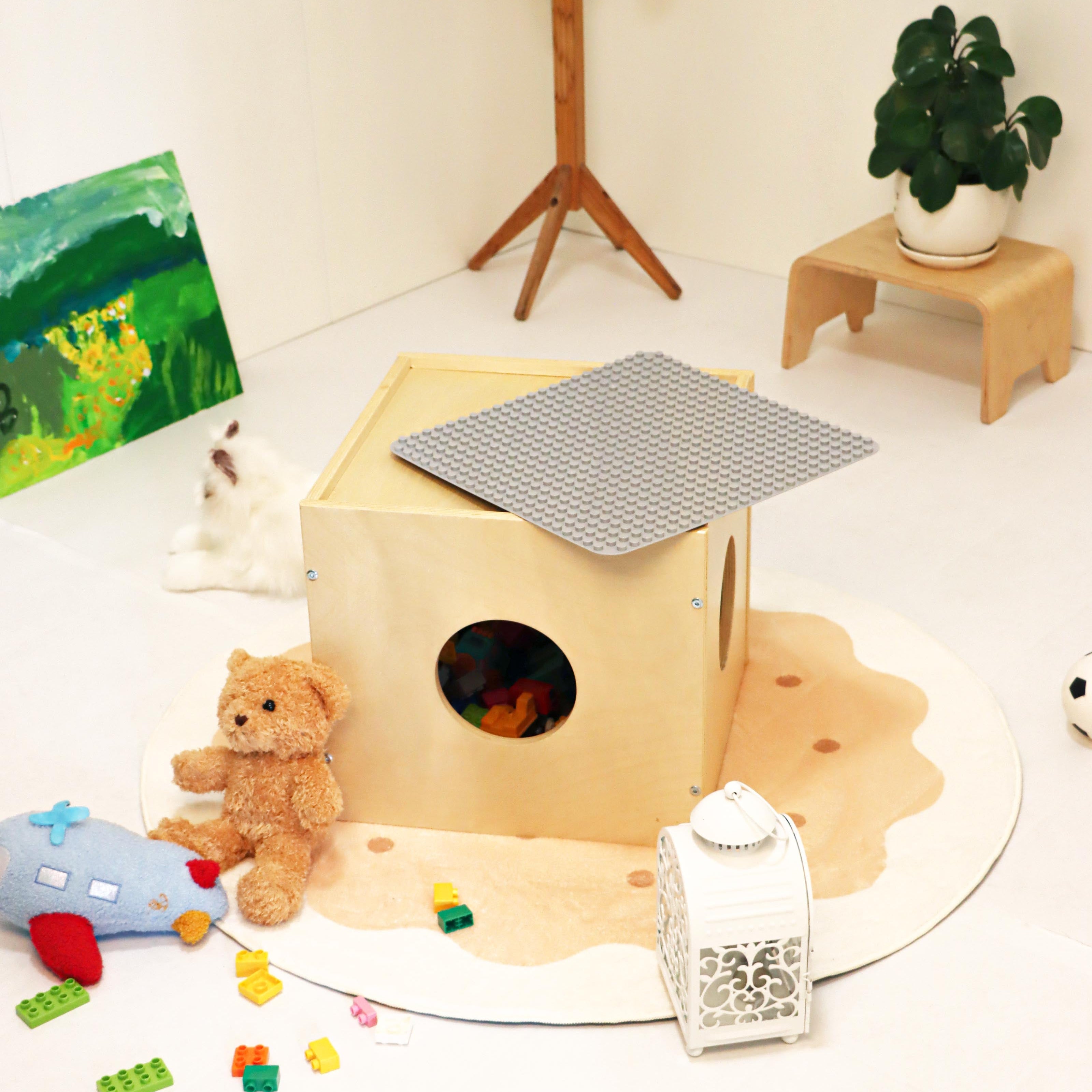 Children's play area with a wooden fort, teddy bear, and toys on a white floor.