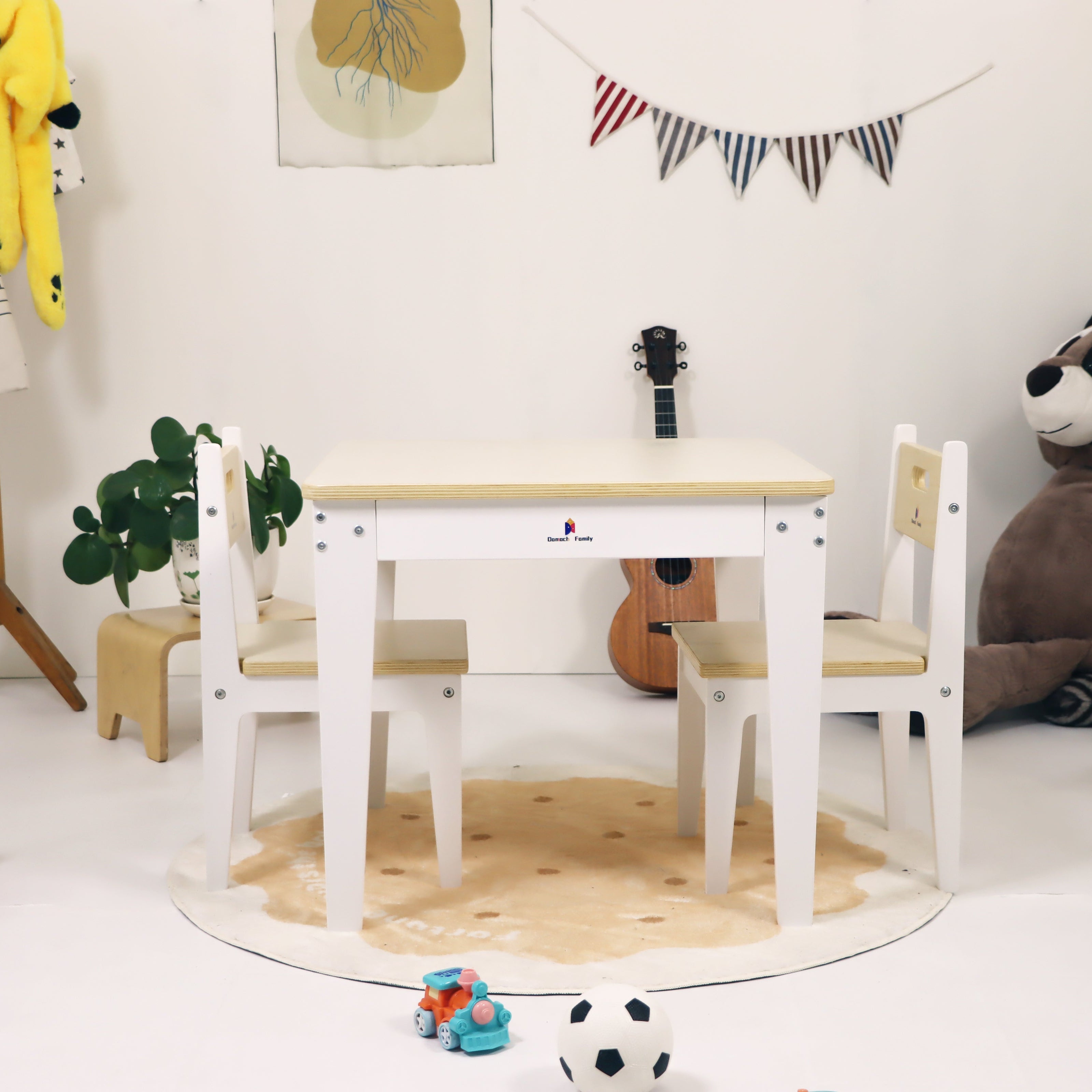 Children's playroom with a wooden table and chairs, toys, and a teddy bear.