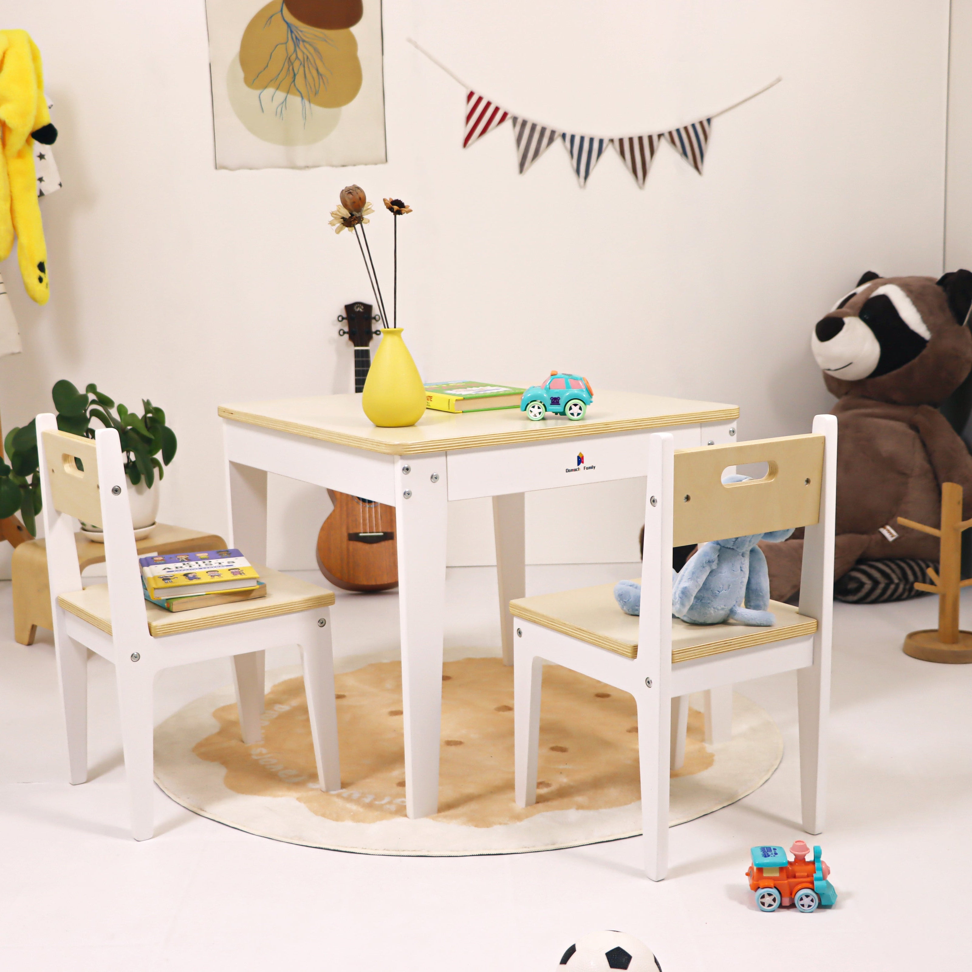 Children's play area with wooden table and chairs, toys, and decorations.