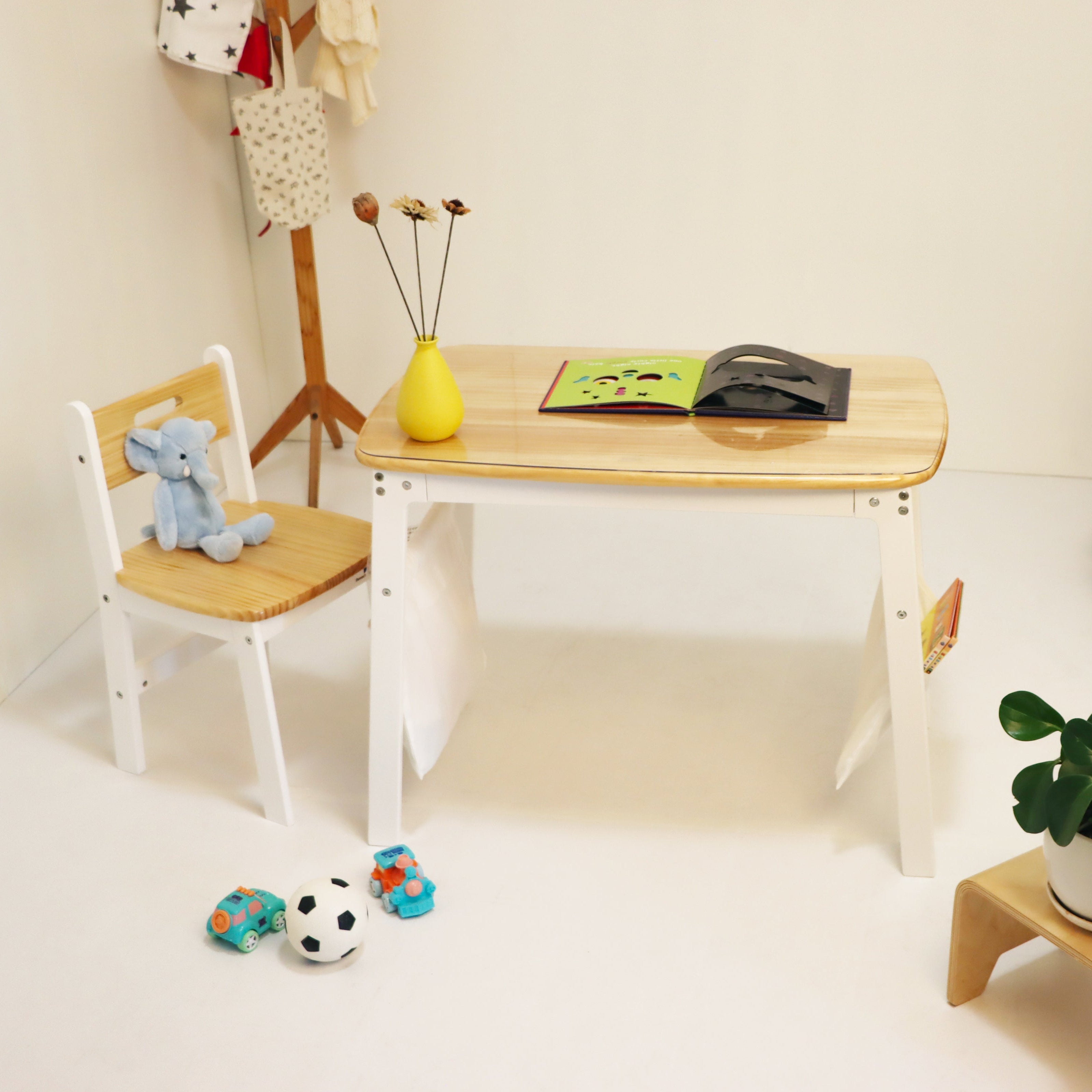 Children's table and chair set with toys and a plant in a room.