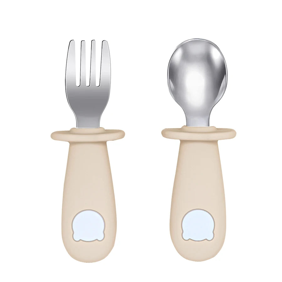Set of baby fork and spoon with beige handles on a white background