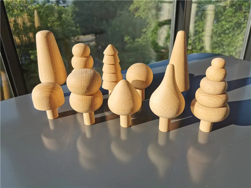 Set of wooden tree-shaped toys on a reflective surface with a blurred outdoor background