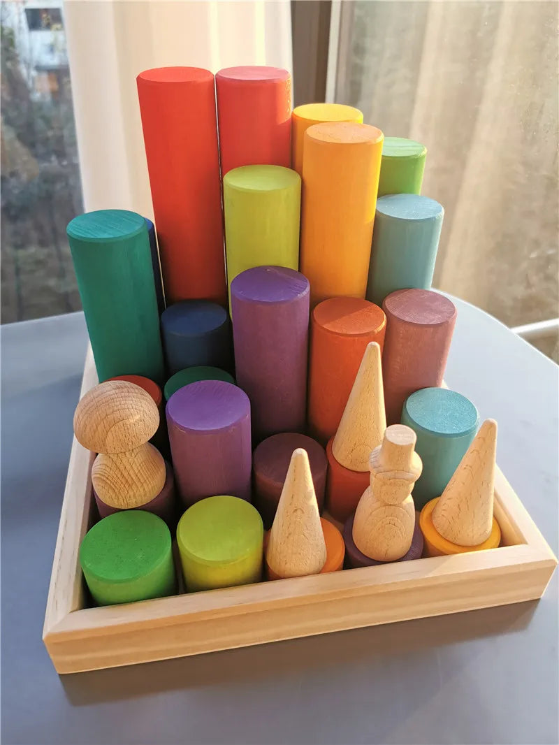 Colorful wooden geometric cylinder shapes in a wooden tray on a light surface.