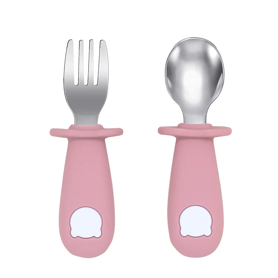 Set of pink children's fork and spoon with white cloud designs on a white background