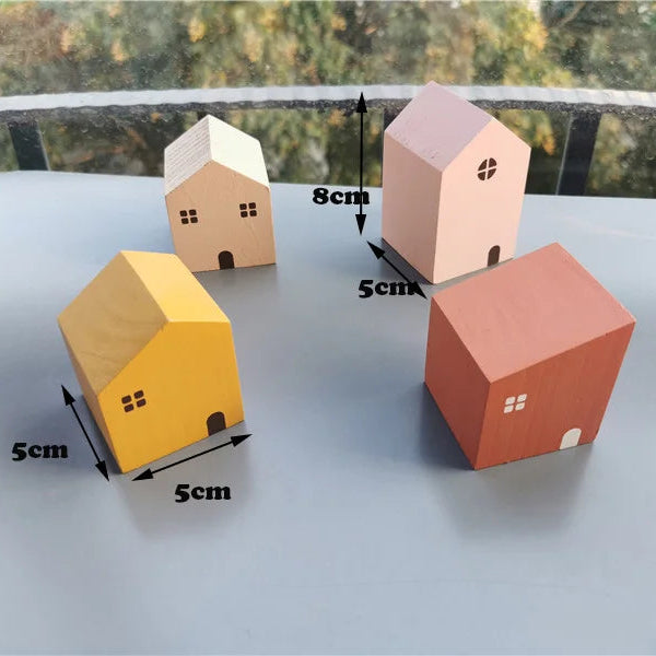 Four small model houses with dimensions indicated on a flat surface.