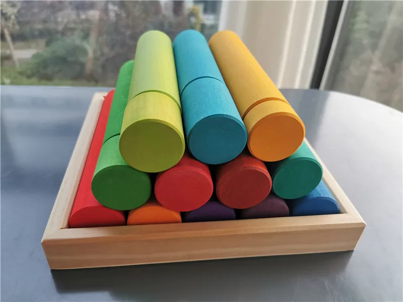 Colorful cylindrical blocks in a wooden tray on a reflective surface