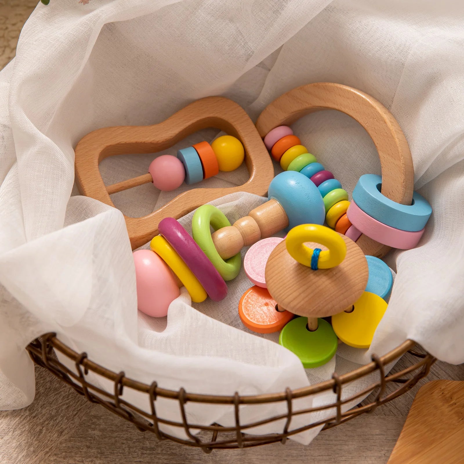 Colorful wooden baby teething toy set on a white fabric background