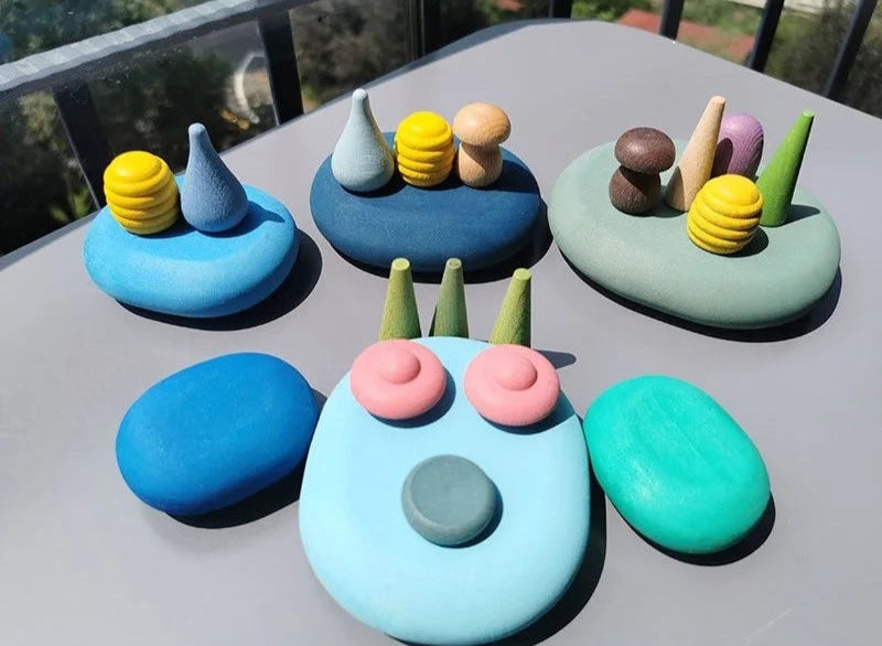 Colorful stone sculptures resembling faces on a gray surface with a blurred outdoor background.