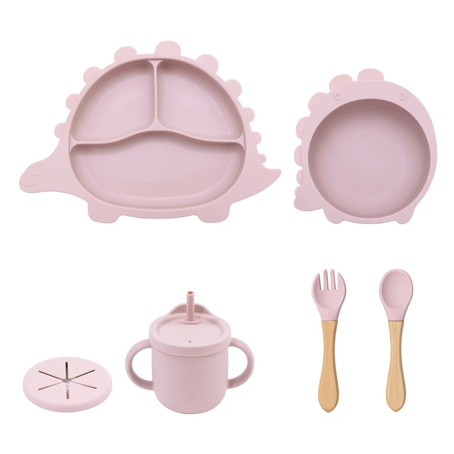 Pink children's dining set including plate, bowl, cup, fork, and spoon on a white background