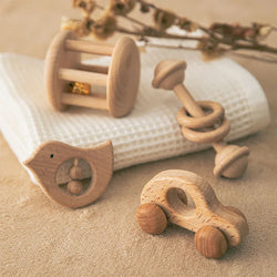 Montessori Baby Beech Wood Rattle Sets featuring a close-up of a wooden rattle, a toy car, and a bird-shaped object, ideal for developing motor skills.