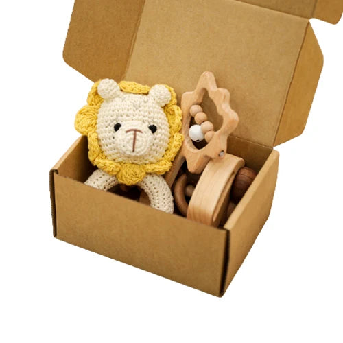 Crocheted lion toy and wooden ring in a cardboard box on a white background