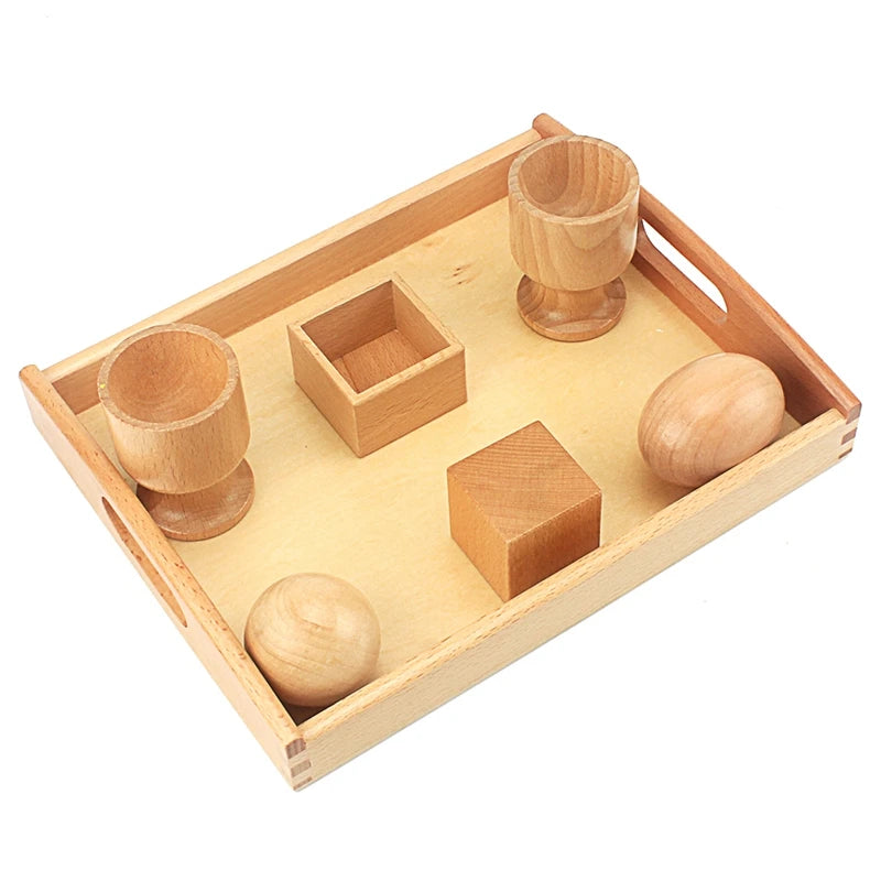 Egg, ball and cube with their cups and box on a tray