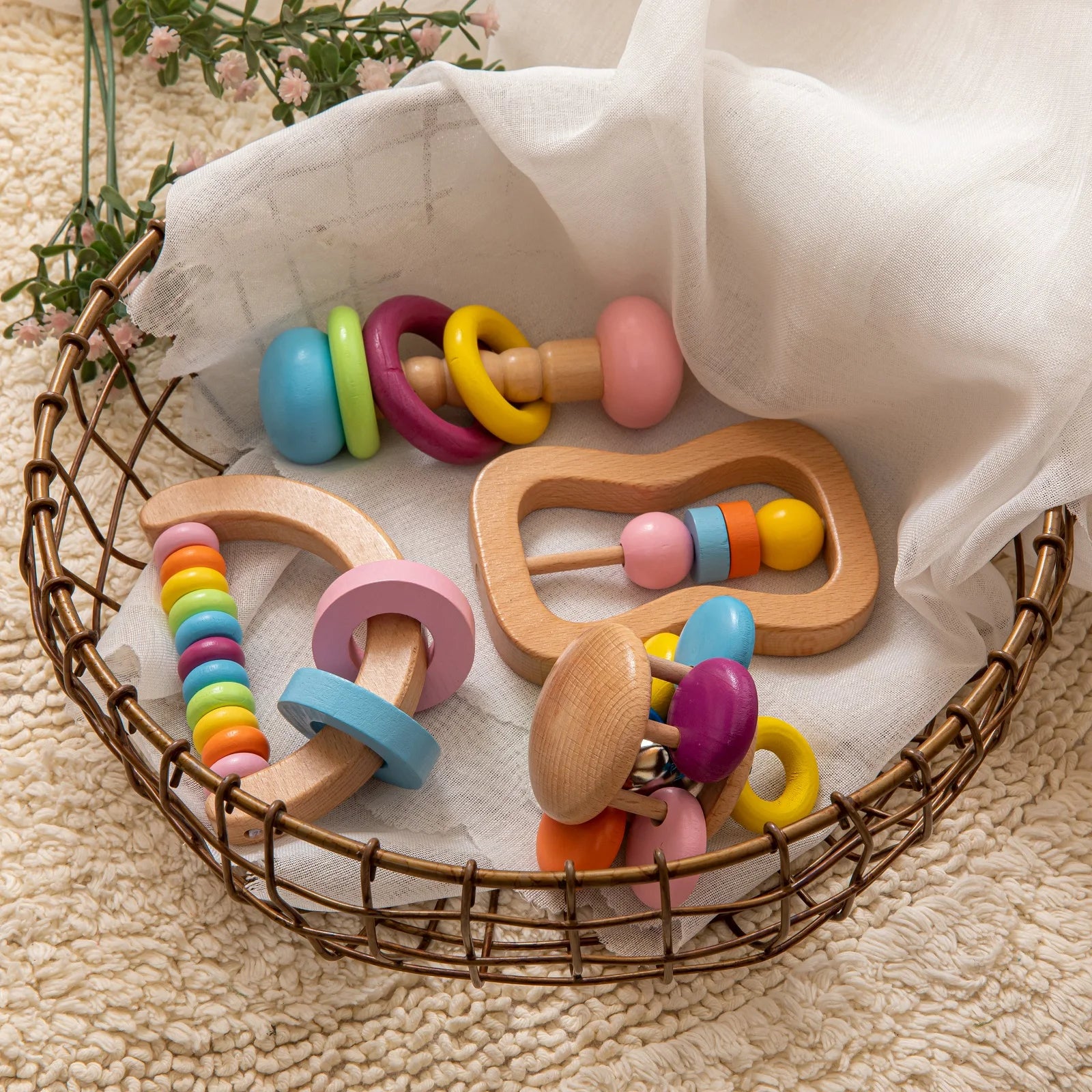 Colorful wooden baby rattle set in a woven basket on a soft surface.