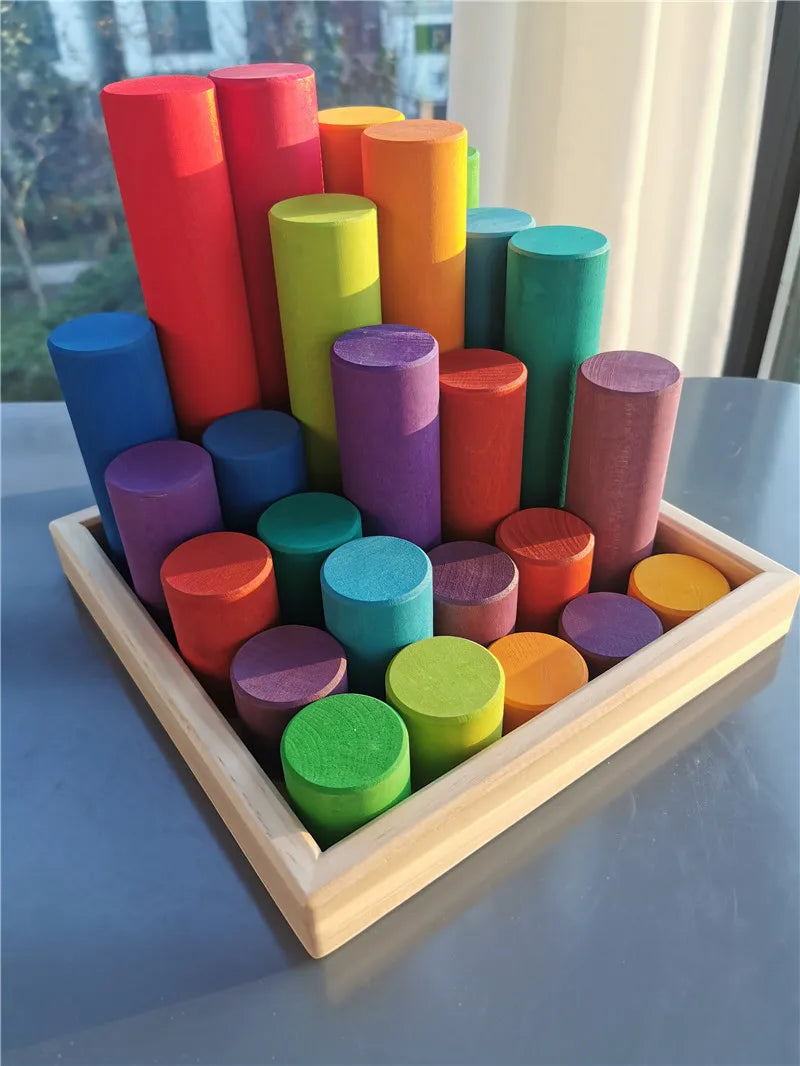 Colorful cylindrical blocks in a wooden tray on a reflective surface