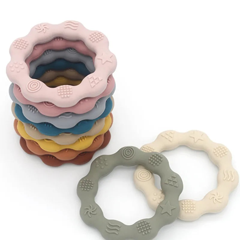 Stack of wavy silicone teething rings in soft colors