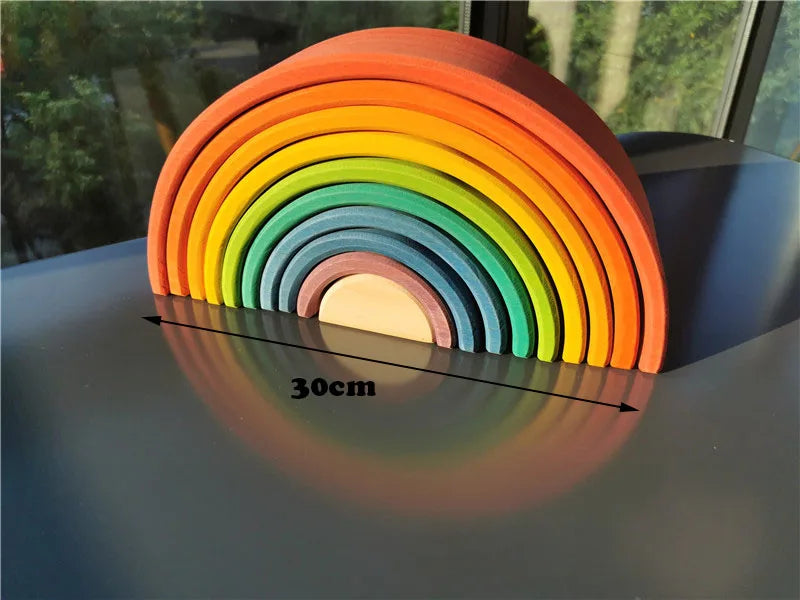 Colorful wooden rainbow toy archs on a reflective surface with a measurement label.