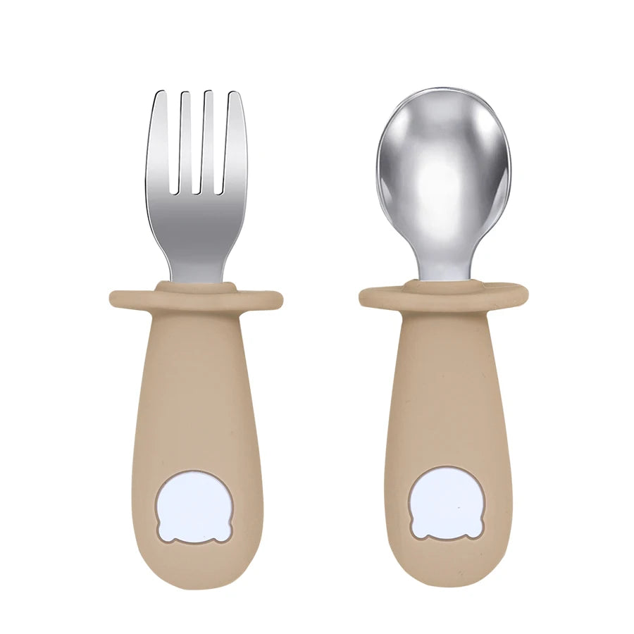 Set of children's fork and spoon with beige handles on a white background