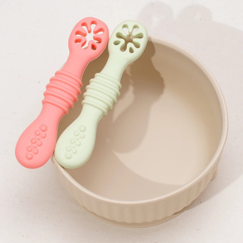 Coral and sage silicone spoons resting in a cream bowl