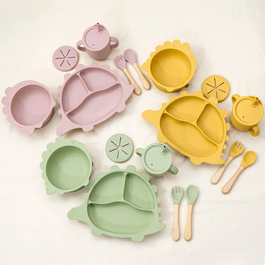 Set of colorful children's tableware including bowls, plates, cups, and utensils on a white background