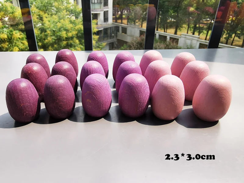 Purple and pink eggs on a reflective surface with a blurred outdoor background