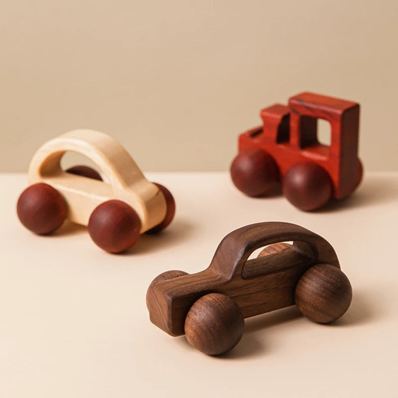 Three wooden toy cars on a beige surface
