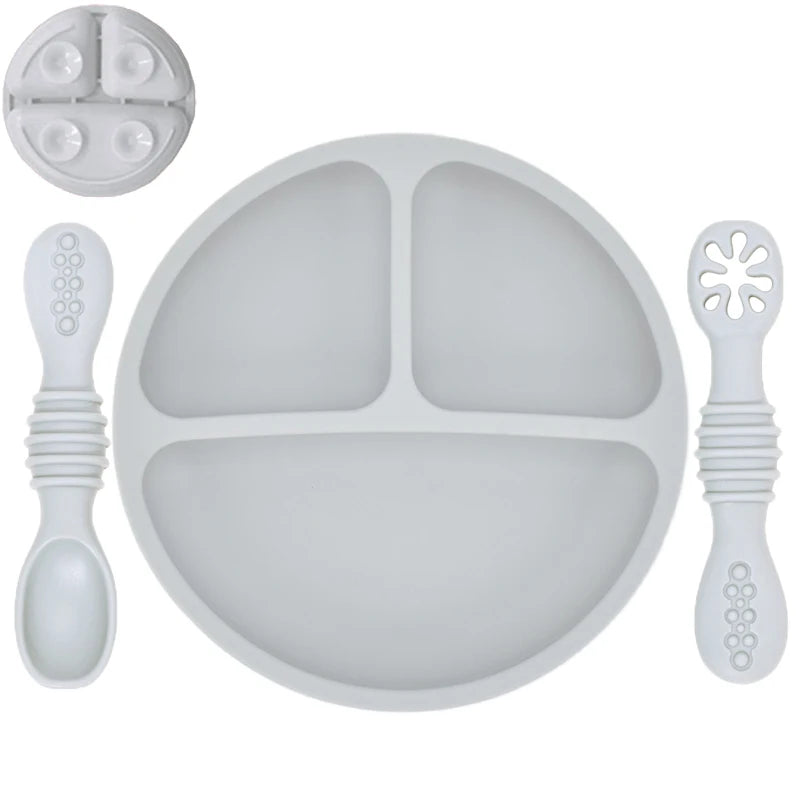 Gray silicone plate with divided sections, a spoon, and a fork on a white background