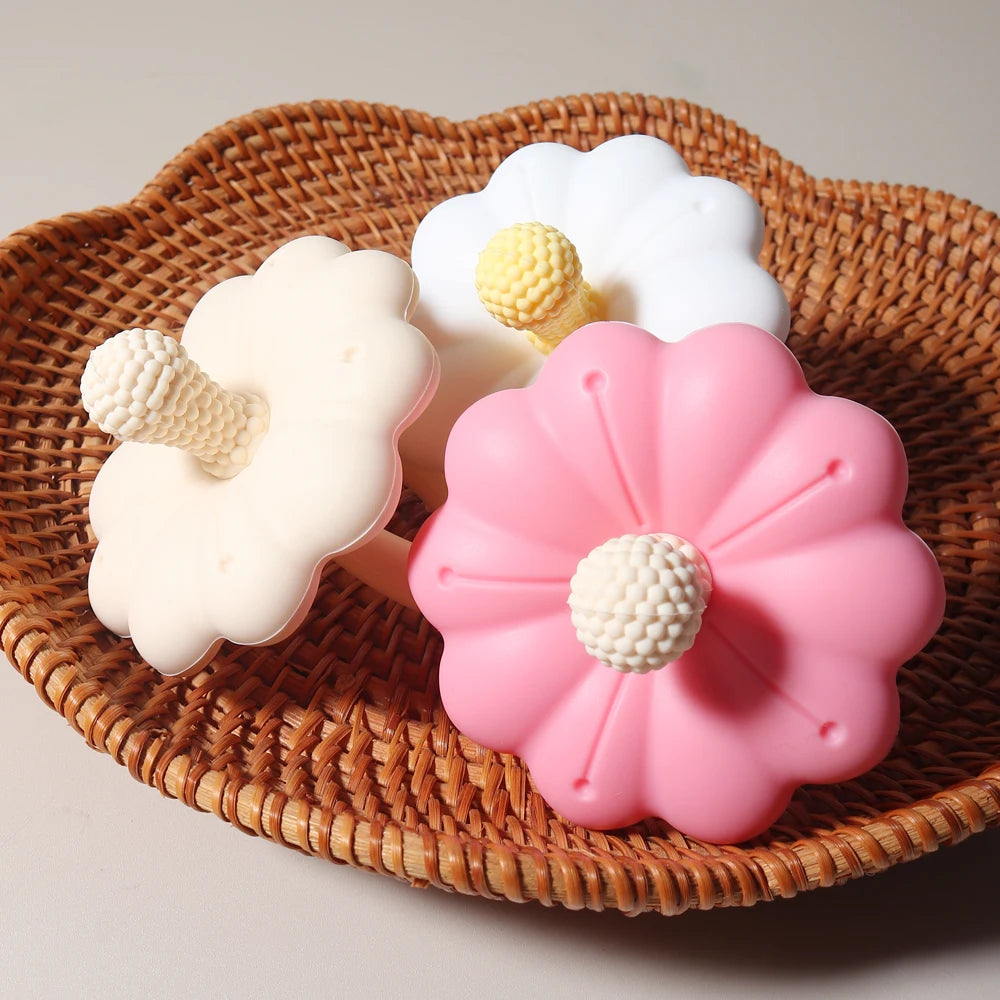Three flower-shaped silicone molds on a woven surface