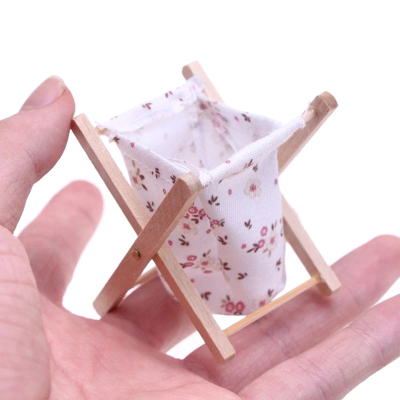 Small wooden cradle with floral fabric held in a hand on a white background