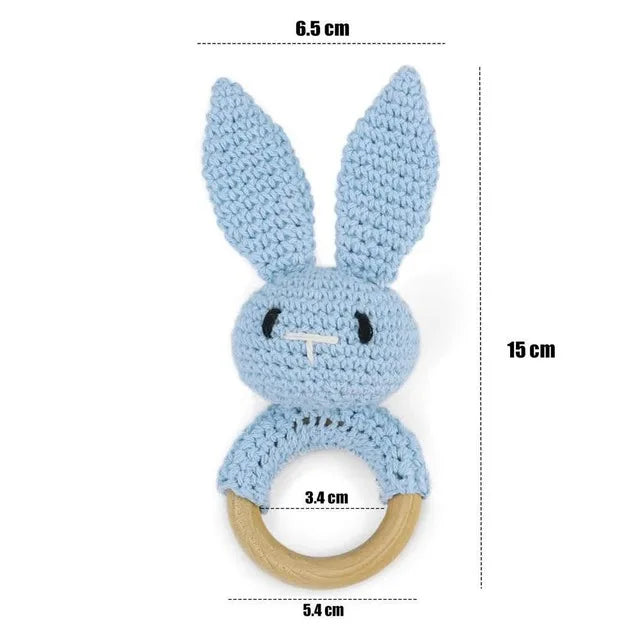 Blue crocheted bunny rattle with wooden ring and measurements on a white background