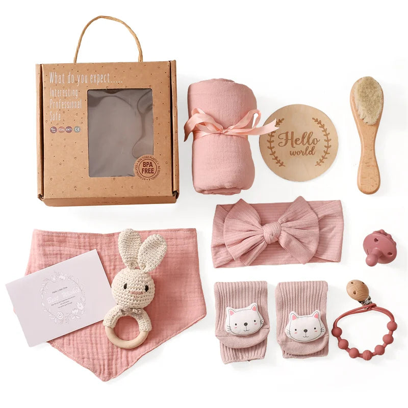 Collection of baby items including a pink swaddle, headband, and toys on a white background