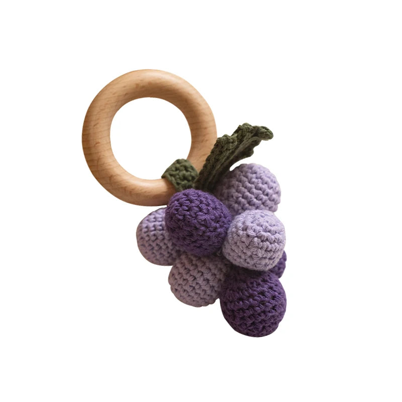 Wooden teething ring with purple crocheted grapes on a white background