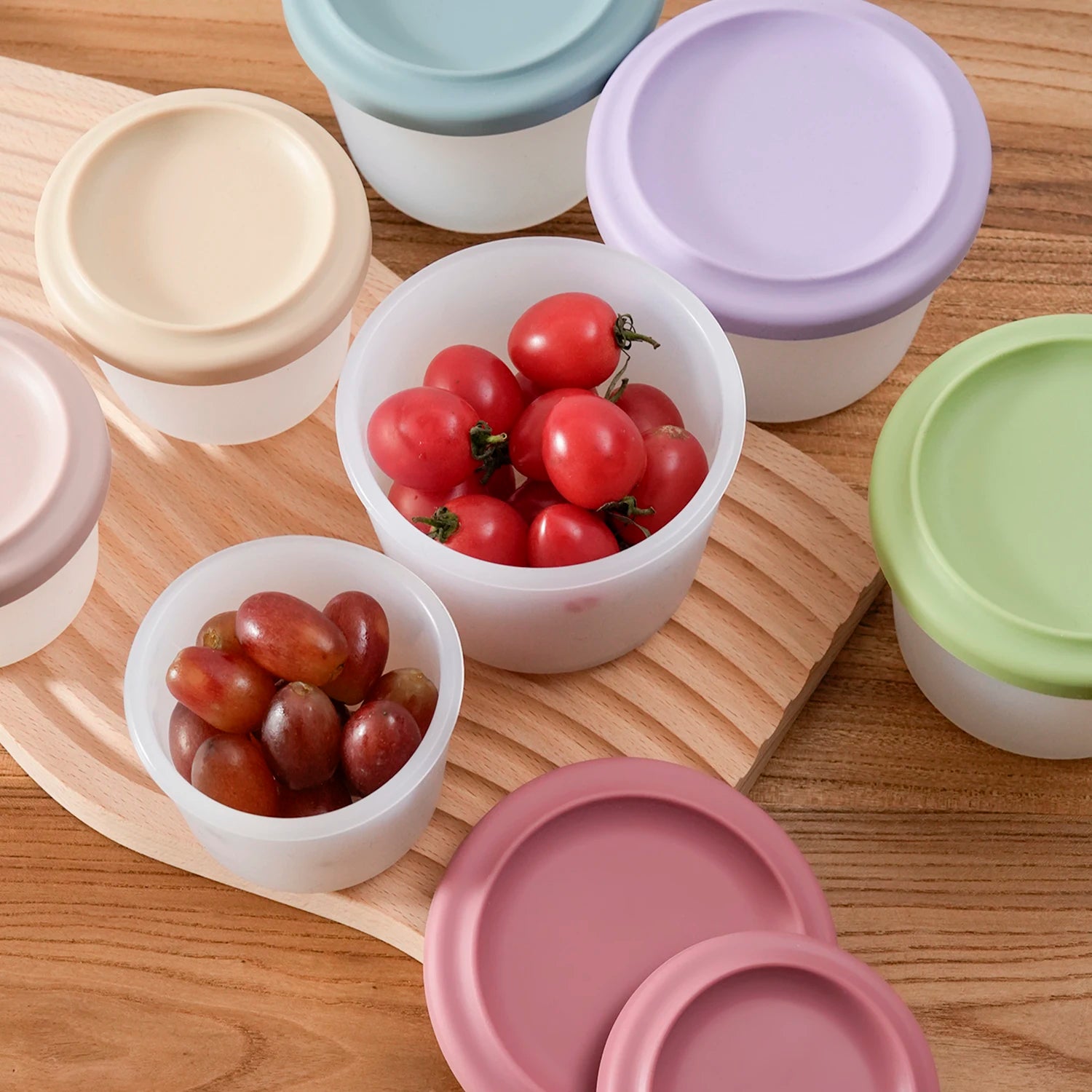 Round silicone containers filled with cherry tomatoes and grapes