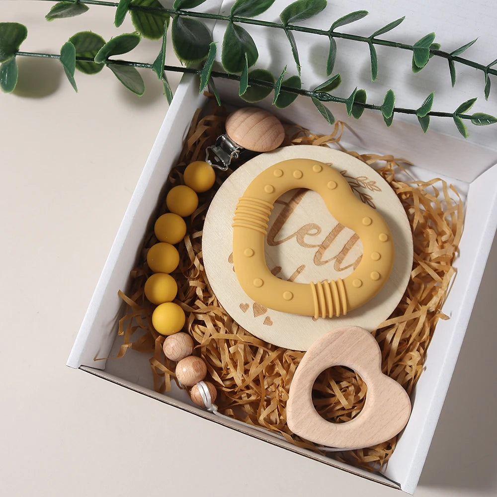 Baby teething ring set with yellow, beige, and wooden elements in a decorative box.