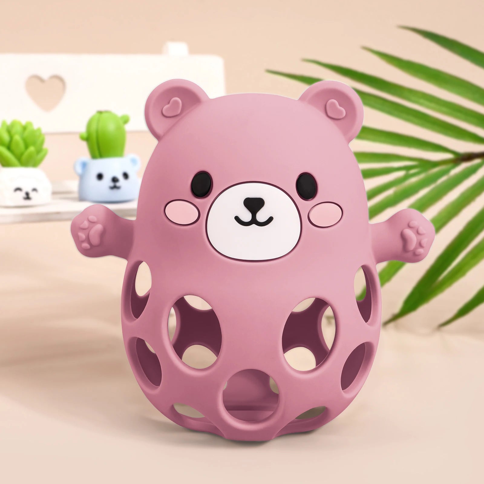 Pink bear-shaped toy on a light background with plants in the background