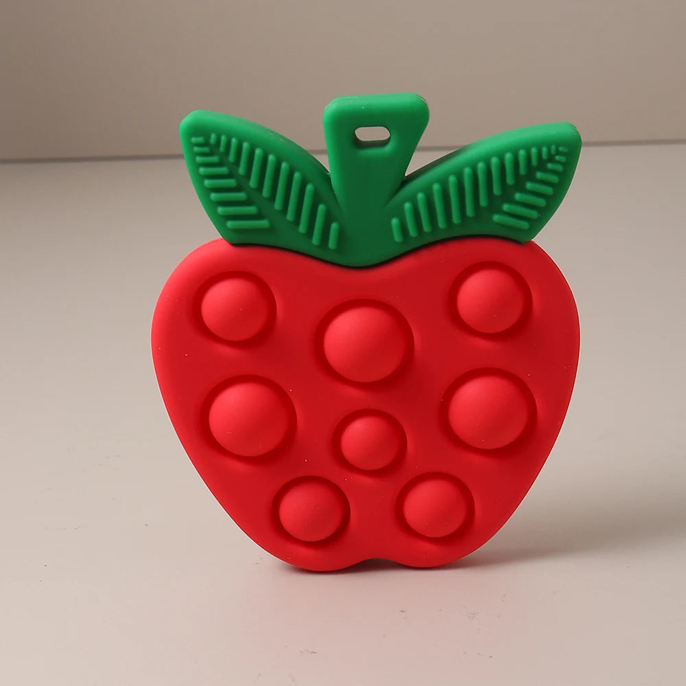 Red apple-shaped pop-it toy with green stem on a beige background