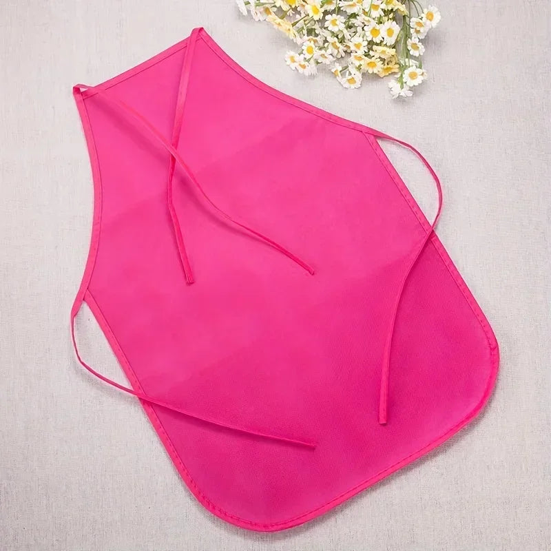 Pink apron on a light gray surface with a small bouquet of flowers in the corner.