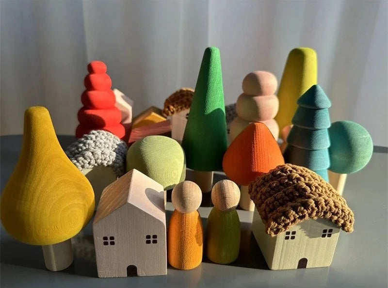 Colorful wooden toy village with houses, trees, and people on a gray surface.