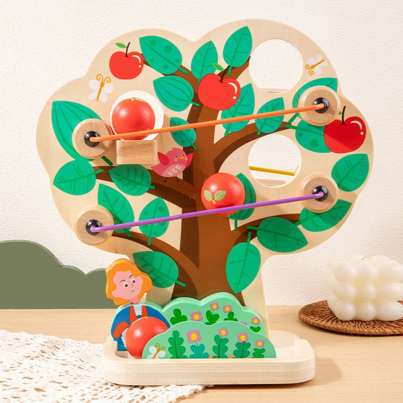 Wooden toy resembling a heart-shaped apple tree with red apples and green leaves on a light background.