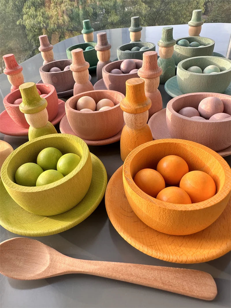 Colorful wooden toys including bowls, spoons, and figurines on a gray surface.